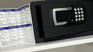 A microwave with a keypad and a manual on a shelf. - Bella Ciao Firenze (Florence)