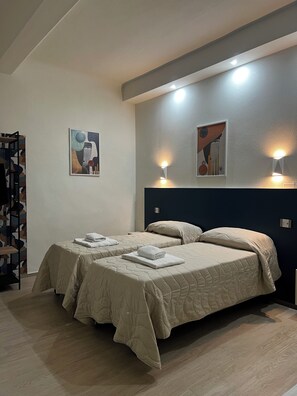 Habitación de hotel con dos camas, un cuadro grande en la pared y suelo de madera.
