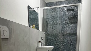 A modern bathroom with a toilet, bidet, sink, and glass shower enclosure. - Bella Ciao Firenze (Florence)