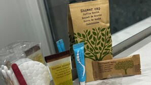 A bathroom shelf with various toiletries including a shower cap, a tube of toothpaste, a bar of soap, and a bag of shower gel. - Bella Ciao Firenze (Florence)
