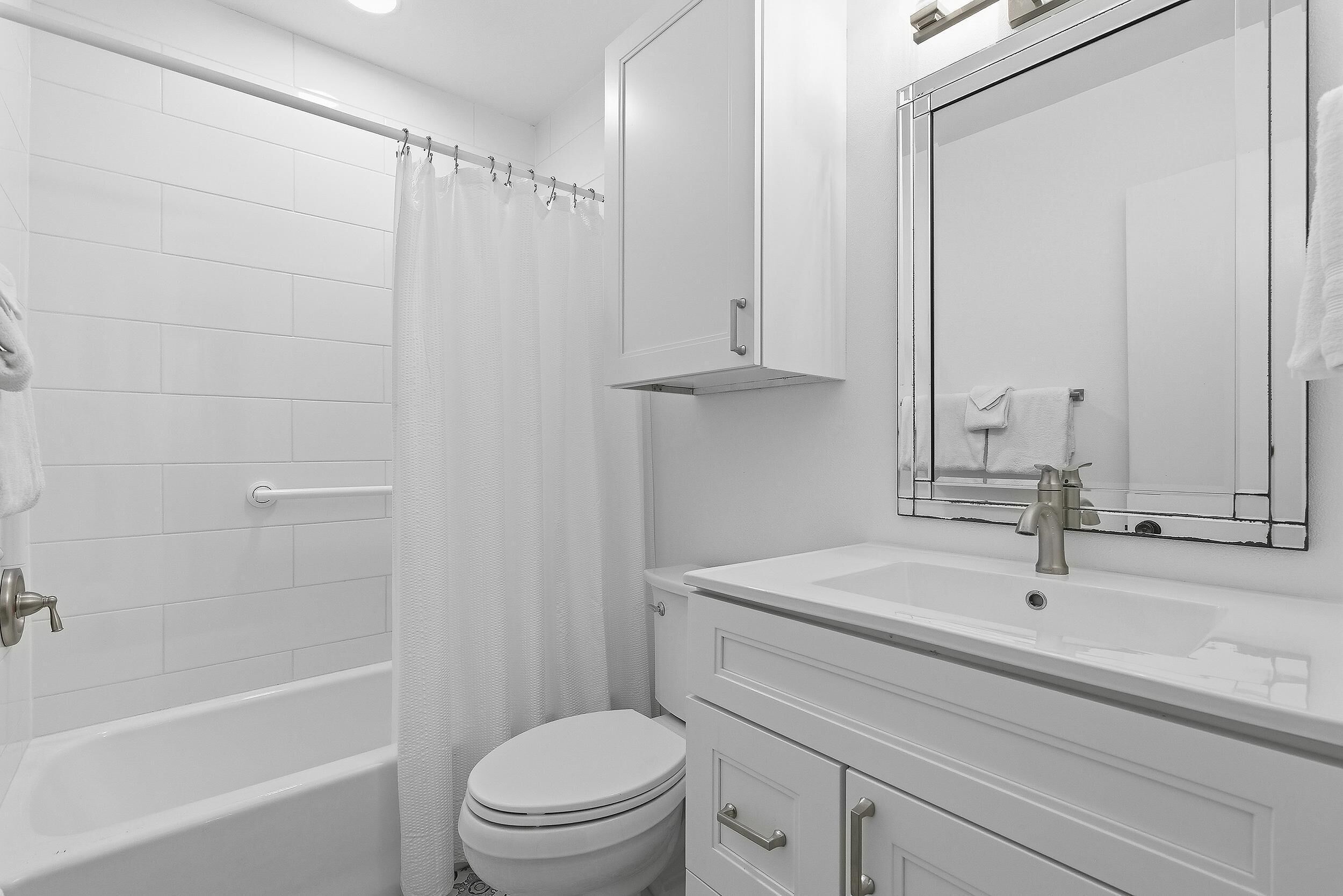A modern bathroom with a bathtub, toilet, and vanity with a mirror.