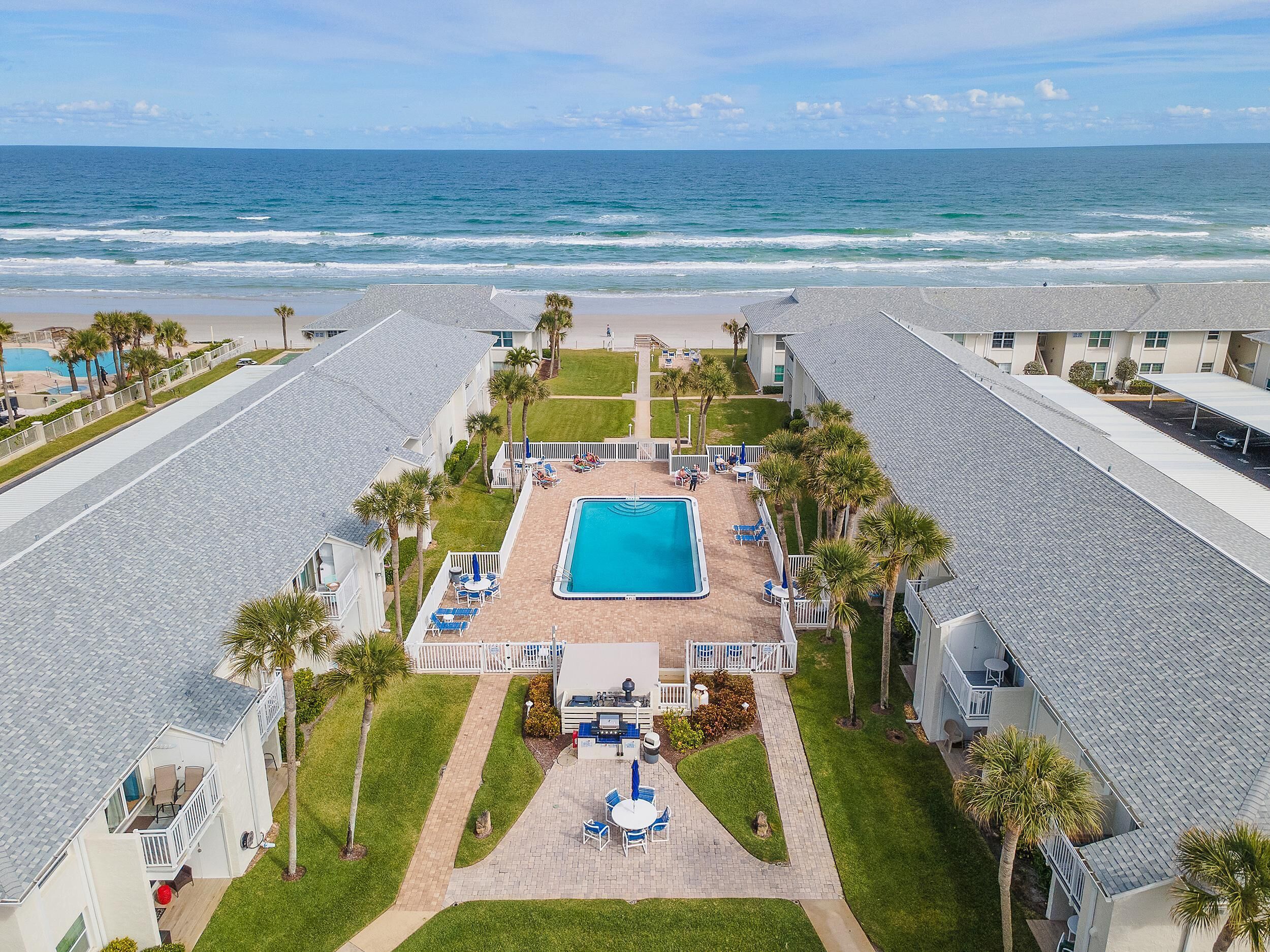 A resort with a swimming pool, beach view, and multiple guest rooms.