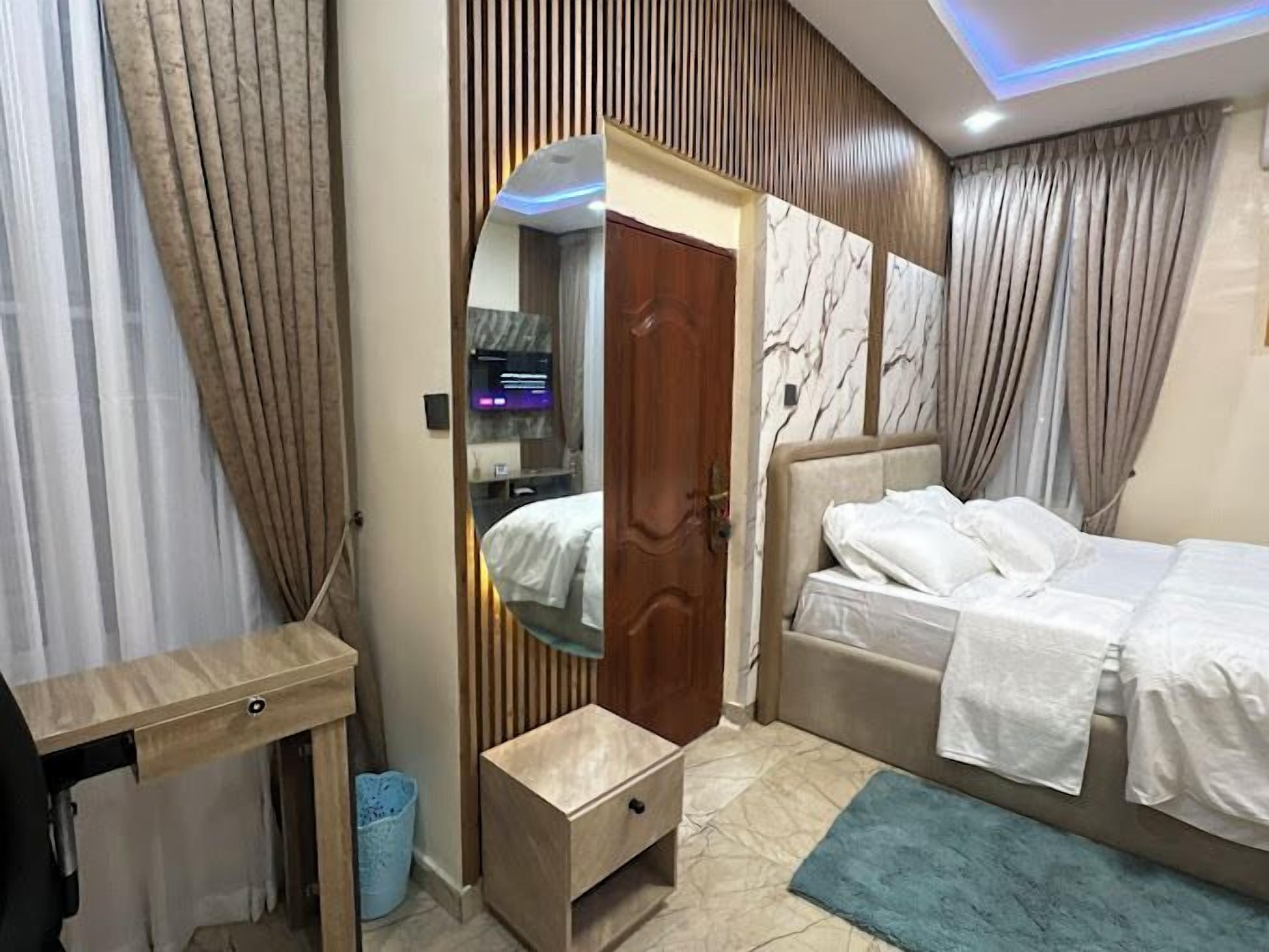 A modern bedroom with a bed, bedside table, and a mirror.