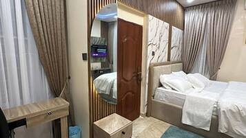 Une chambre à coucher moderne avec un lit, une table de chevet et un miroir.