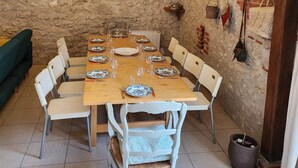 Een eethoek met een rustieke stenen muur, een houten tafel gedekt voor zes personen en een kroonluchter.