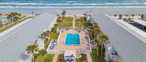 A resort with a swimming pool, beach view, and multiple guest rooms.