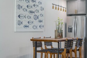 Een eetruimte met een houten tafel en stoelen, een wandlamp en een koelkast op de achtergrond.