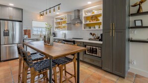 Una cocina moderna con una mesa de comedor de madera, armarios empotrados y electrodomésticos de acero inoxidable.