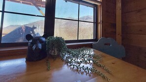 A wooden interior with a large window, a bear-shaped object, and a plant on a table. - Sleepy Bear Log Cabin with View, WiFI (Maggie Valley)