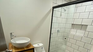 A bathroom with a toilet, sink, and glass shower enclosure.