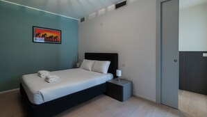 A modern bedroom with a bed, a bedside table, a nightstand, a wall-mounted artwork, and a door. - Italianway Comfort - Lazzaro Papi 14 C (Milan)