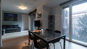 A modern living room with a glass dining table, black chairs, a sofa, and a TV. - Italianway Comfort - Lazzaro Papi 14 C (Milan)