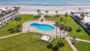 A resort with a swimming pool, beach access, and palm trees.