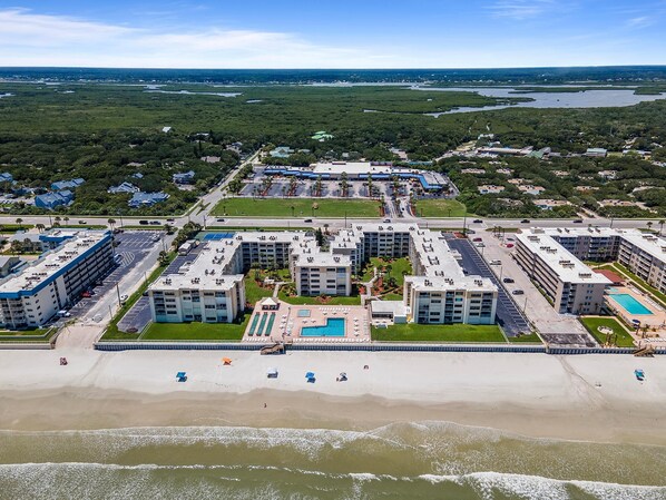 A coastal hotel with multiple buildings, a beach, and a pool area. - Castle Reef 116 (New Smyrna Beach)