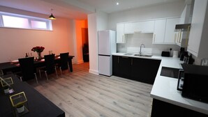 A modern kitchen with white cabinets, a black countertop, and a dining area with a table and chairs. - Lush 5-Bed Home @ Newcastle upon Tyne 
Central | Free parking | Bus @ door step (Newcastle upon Tyne)
