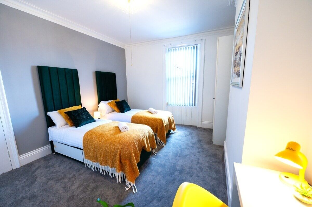 Ein Hotelzimmer mit zwei Betten, einem Schreibtisch, einem Stuhl und einem Fenster mit Jalousien.