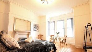 A bedroom with a bed, a fireplace, a dining table with chairs, and a window with blinds. - Lush 5-Bed Home @ Newcastle upon Tyne 
Central | Free parking | Bus @ door step (Newcastle upon Tyne)