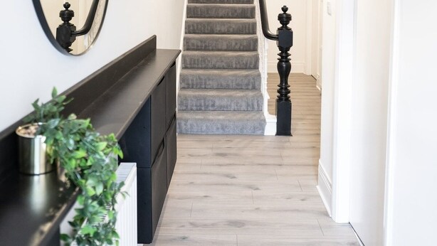 A staircase with a grey carpet, a black balustrade, and a white wall with a large mirror. - Lush 5-Bed Home @ Newcastle upon Tyne 
Central | Free parking | Bus @ door step (Newcastle upon Tyne)