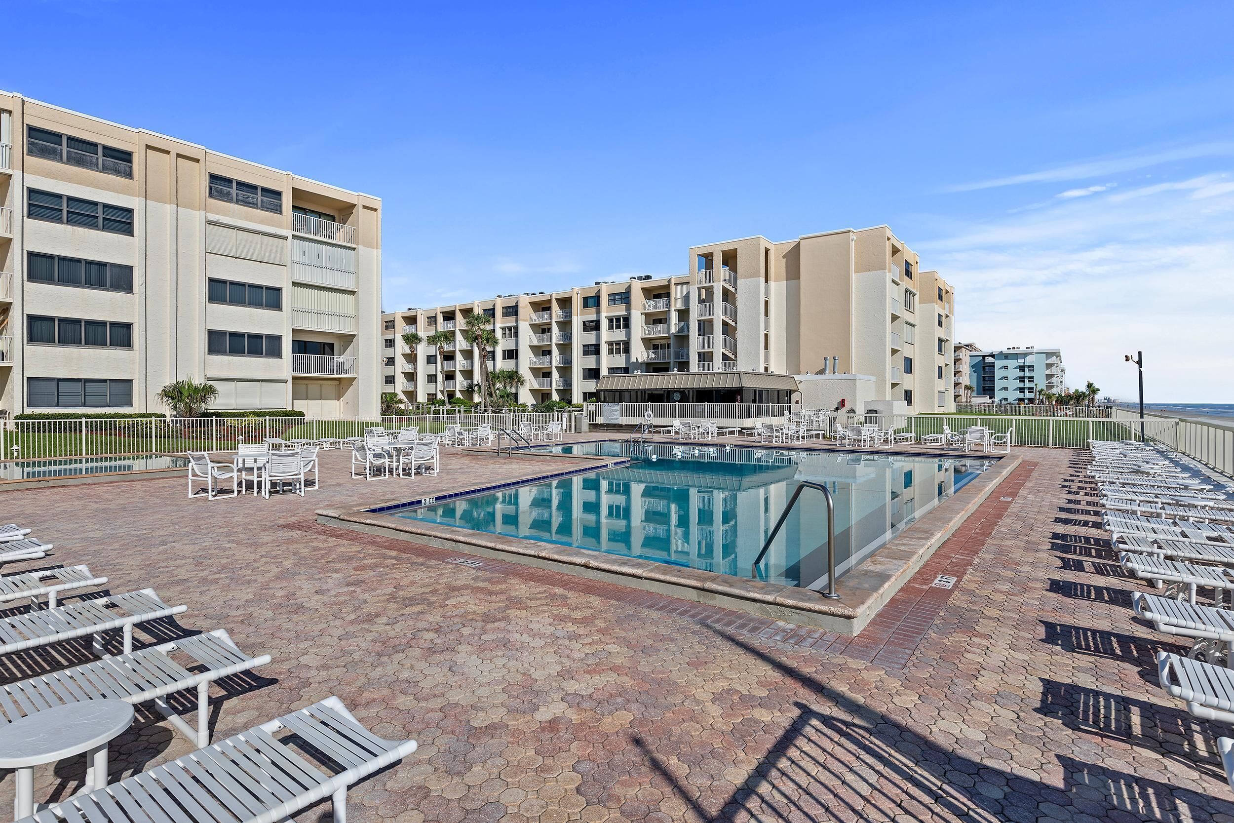 Un espace piscine d’hôtel comprenant plusieurs chaises longues et une piscine.