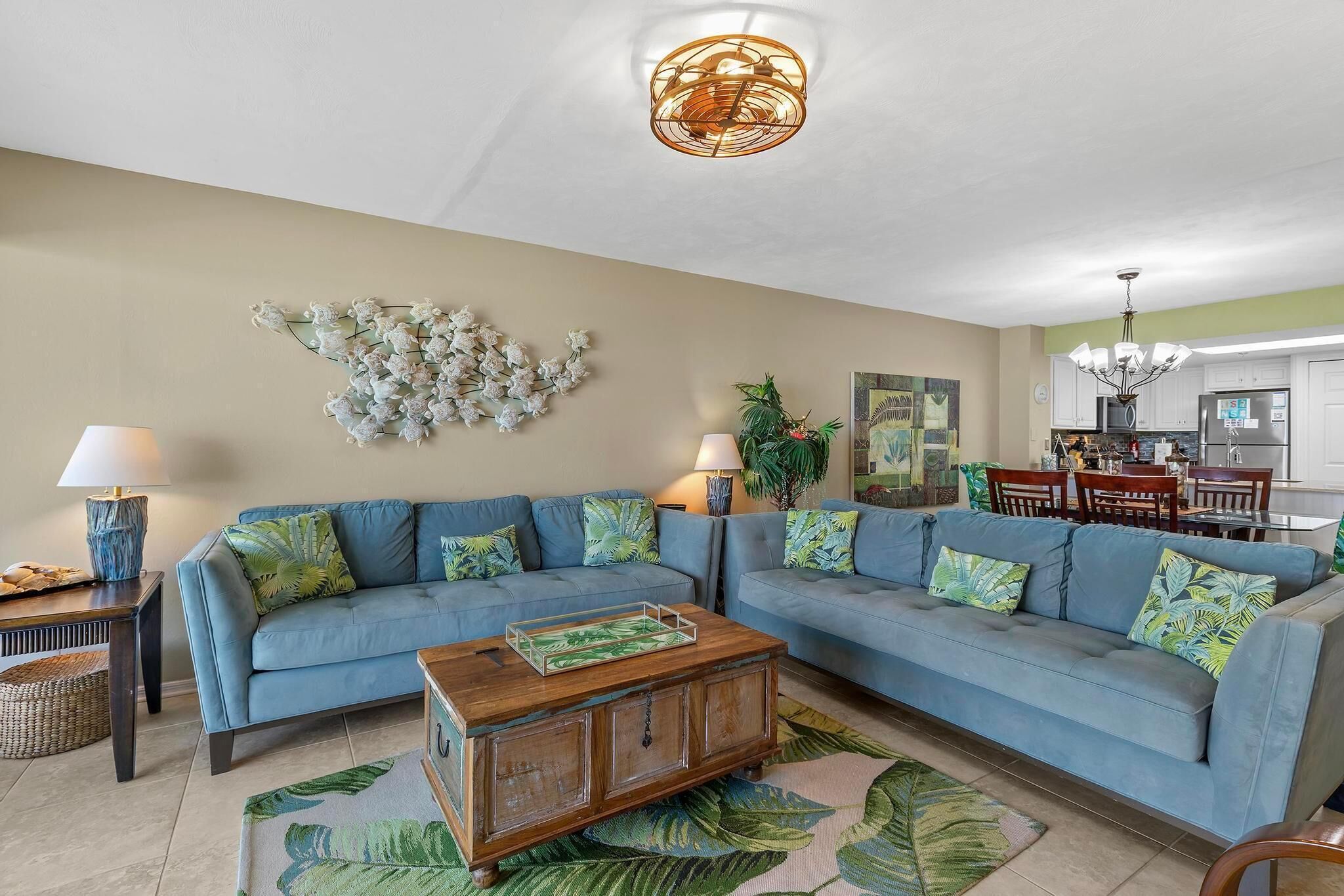 Uma sala de estar com um sofá azul, uma mesa de centro de madeira e um objeto decorativo na parede.