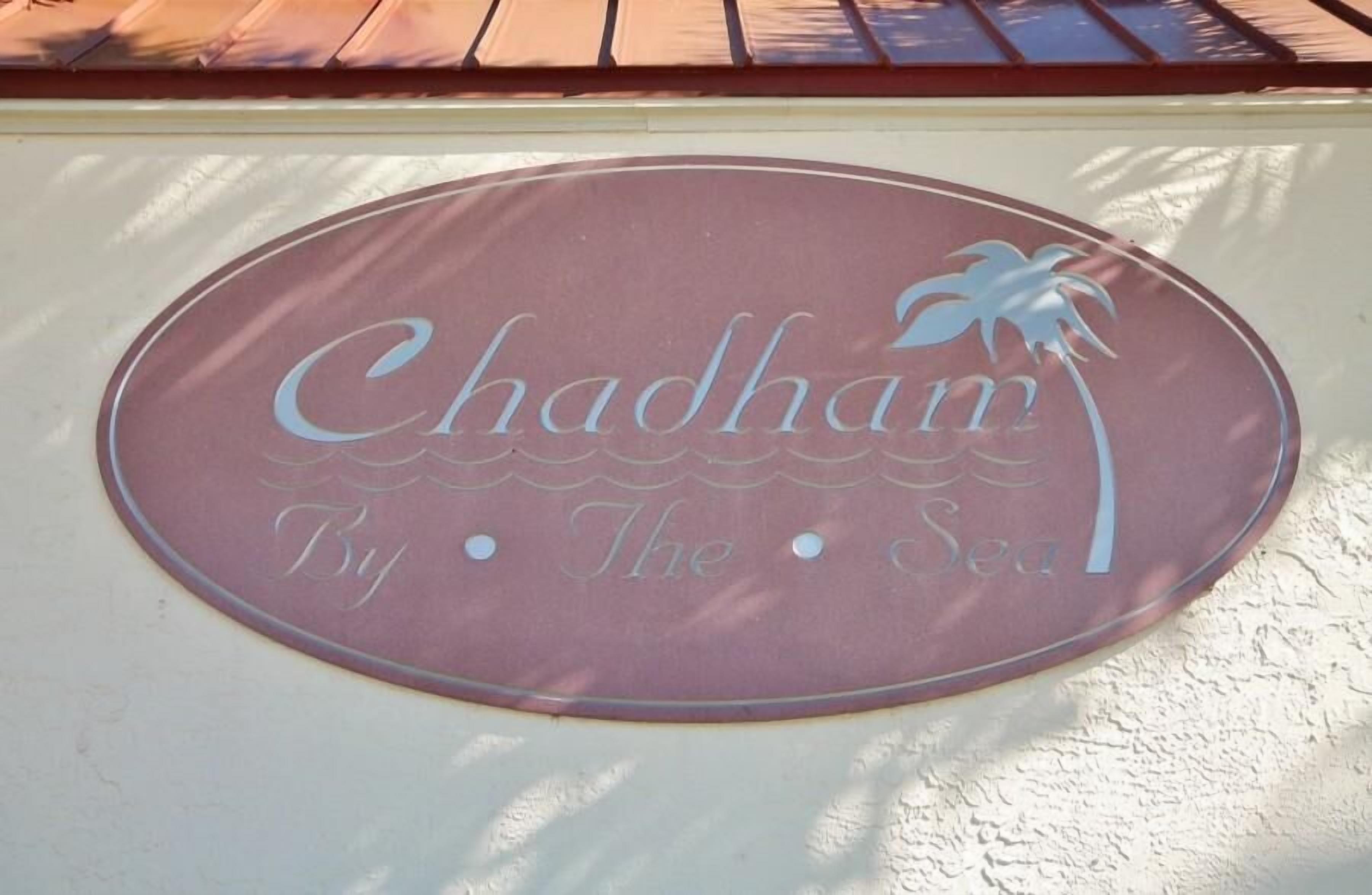 A sign with the text "Chadham By The Sea".