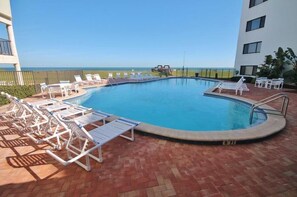 Una piscina con sillas de descanso y vistas a la playa.
