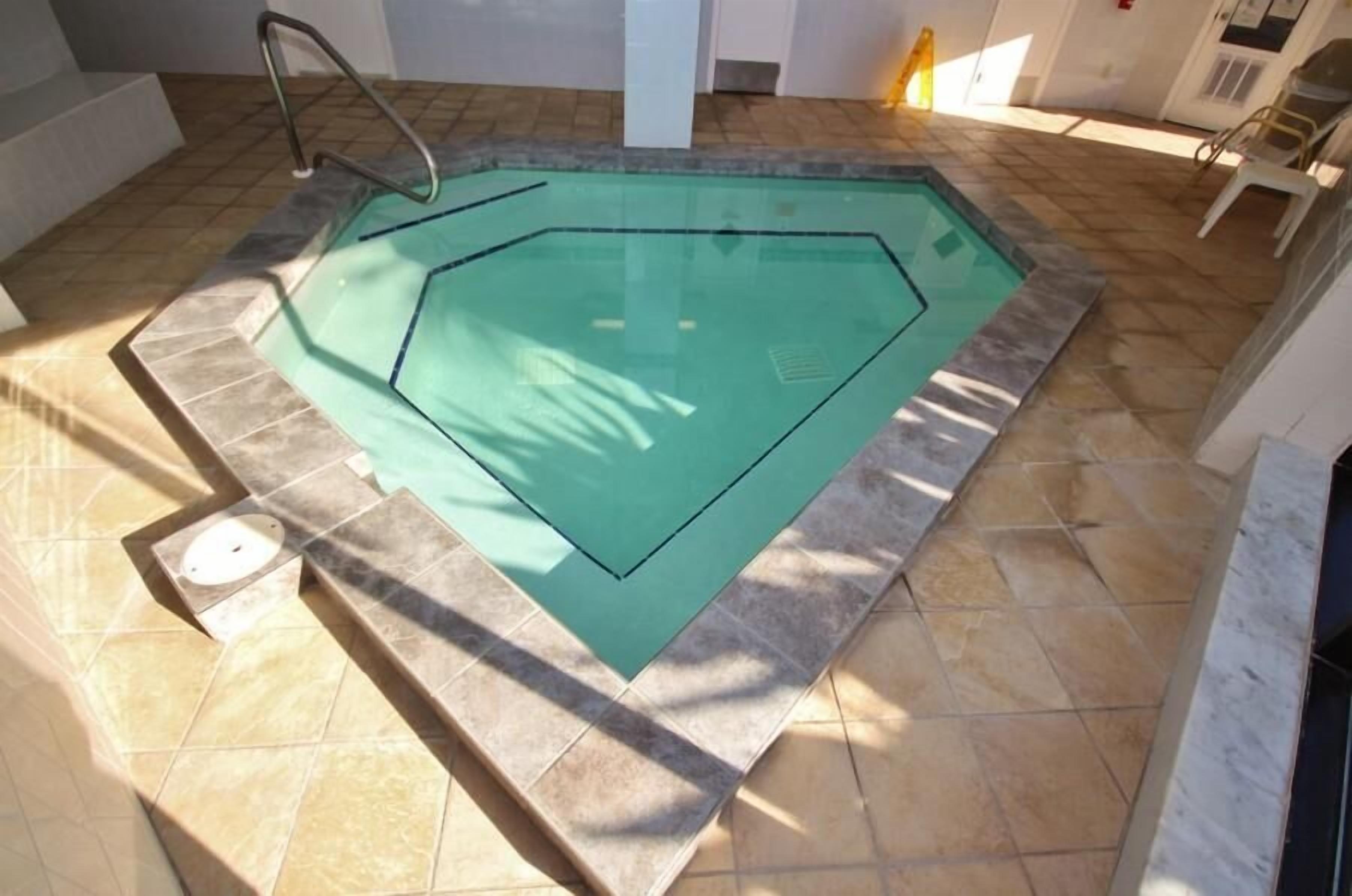 A swimming pool with a tiled floor and a metal ladder.