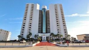 Ein Hochhaus-Hotel mit einem zentralen Glasaufzugsschacht, mehreren Balkonen und einem roten Teppich.