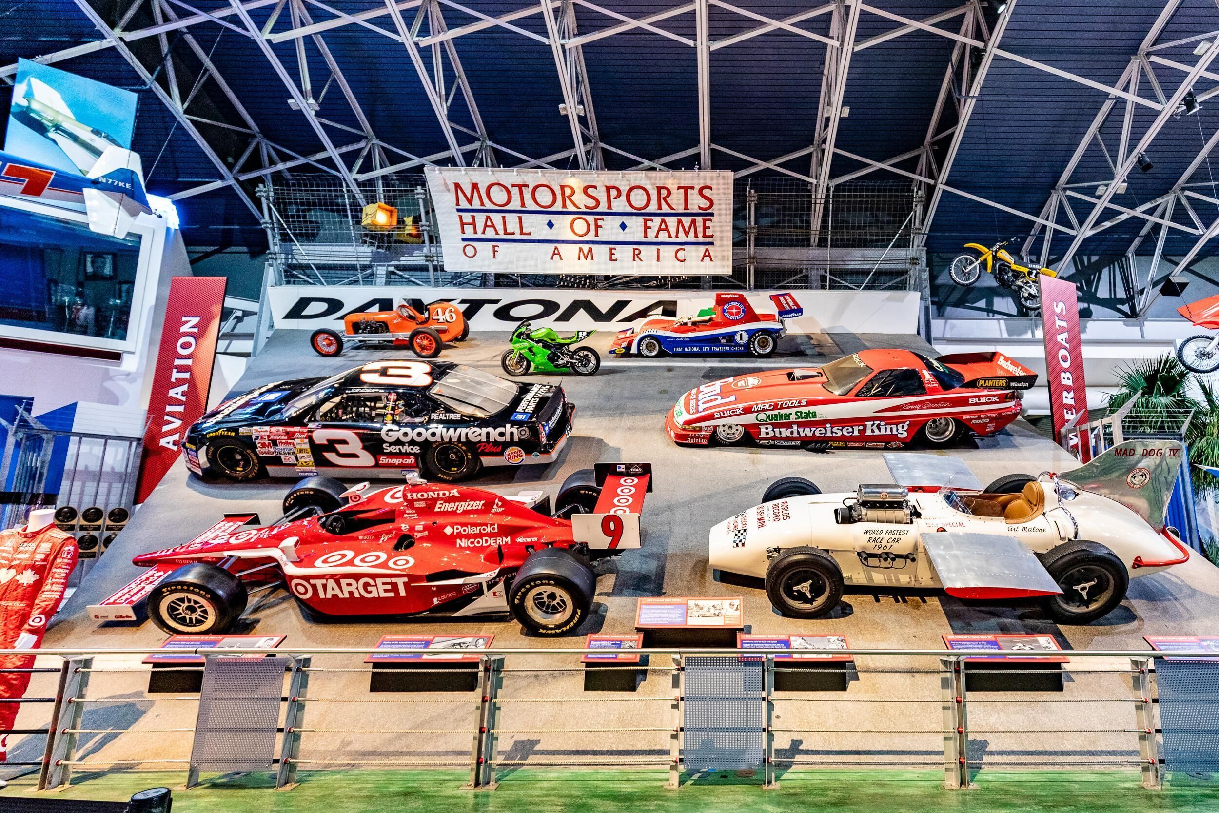 A motorsports exhibit with various racing cars and motorcycles on display.
