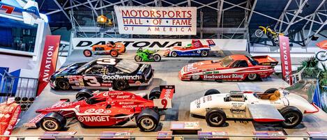 A motorsports exhibit with various racing cars and motorcycles on display.