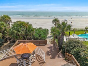 A wooden deck with a table and umbrella, overlooking a beach and a swimming pool. - Decked Out House On Hill St (New Smyrna Beach)