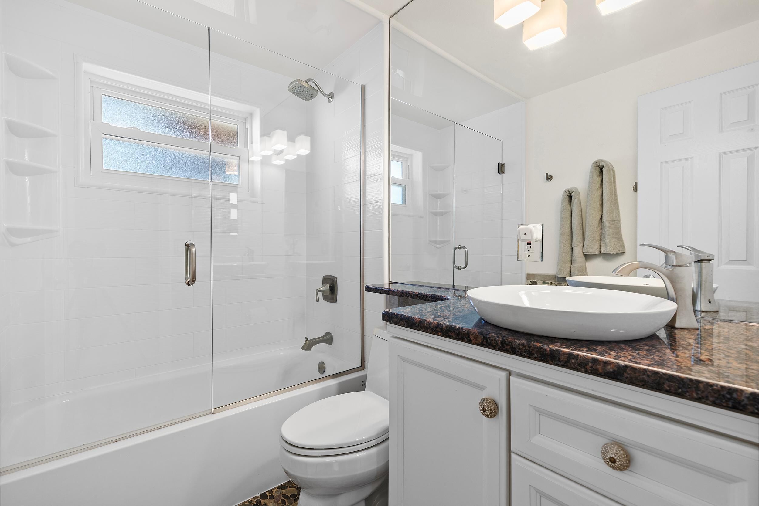 A modern bathroom with a glass-enclosed shower, a white toilet, and a vanity with a sink and countertop.