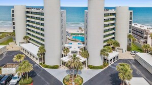 Et hotel med pool, palmer og havudsigt.