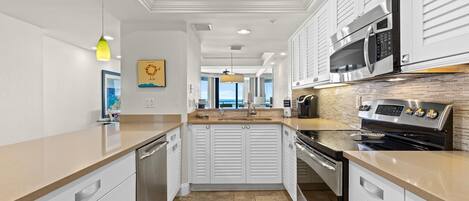 Una cocina moderna con armarios blancos, electrodomésticos de acero inoxidable y vistas al exterior.
