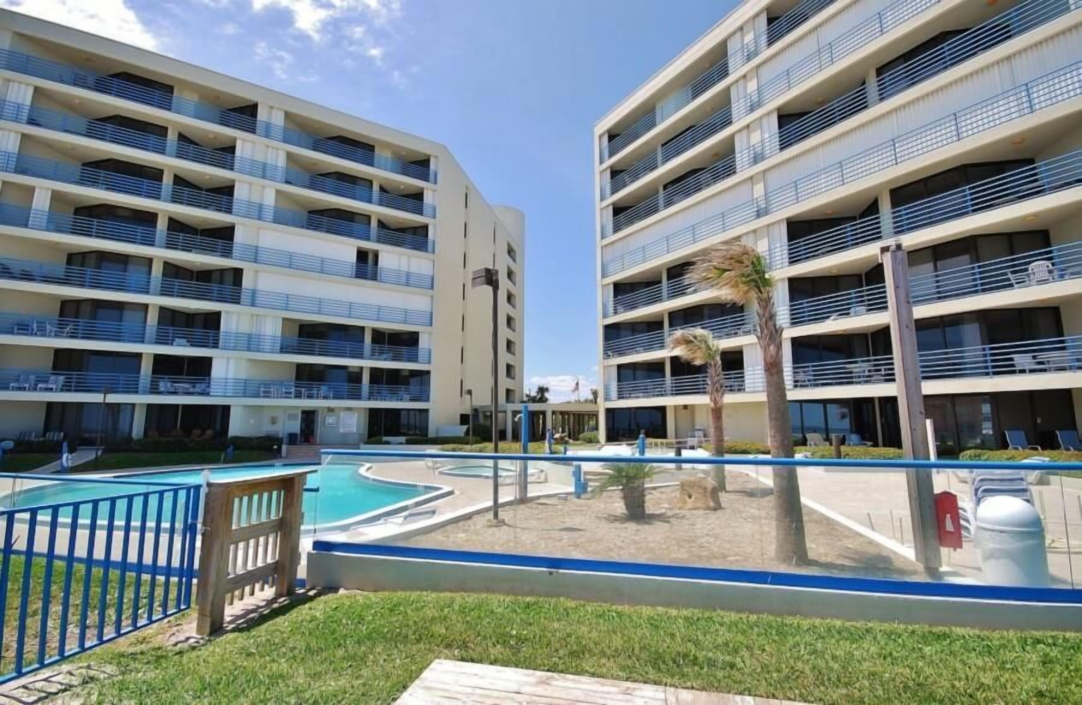 A modern hotel with multiple floors, balconies, and a swimming pool area.
