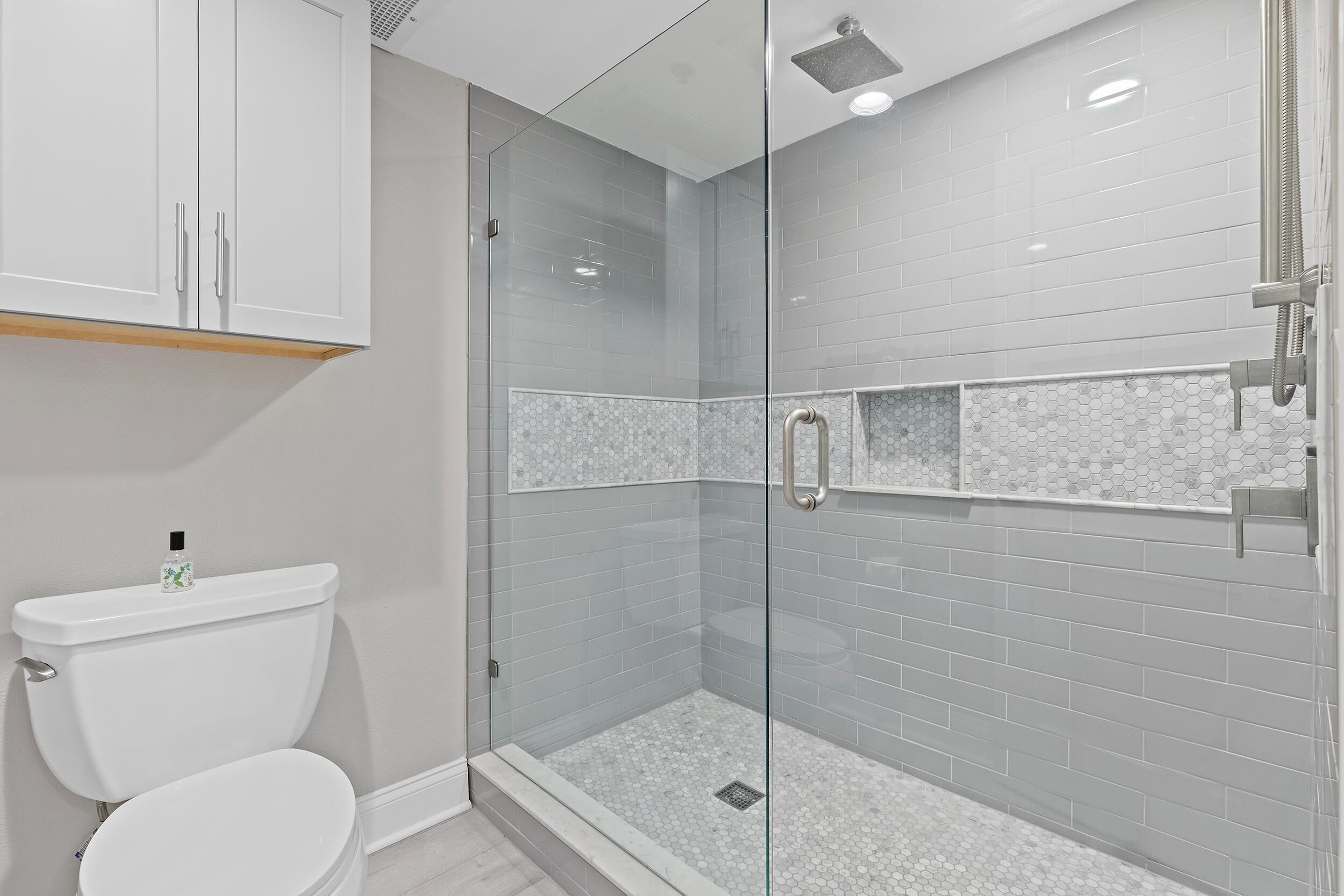 Une salle de bain moderne dotée d’une douche à parois de verre, de toilettes et d’un lavabo.