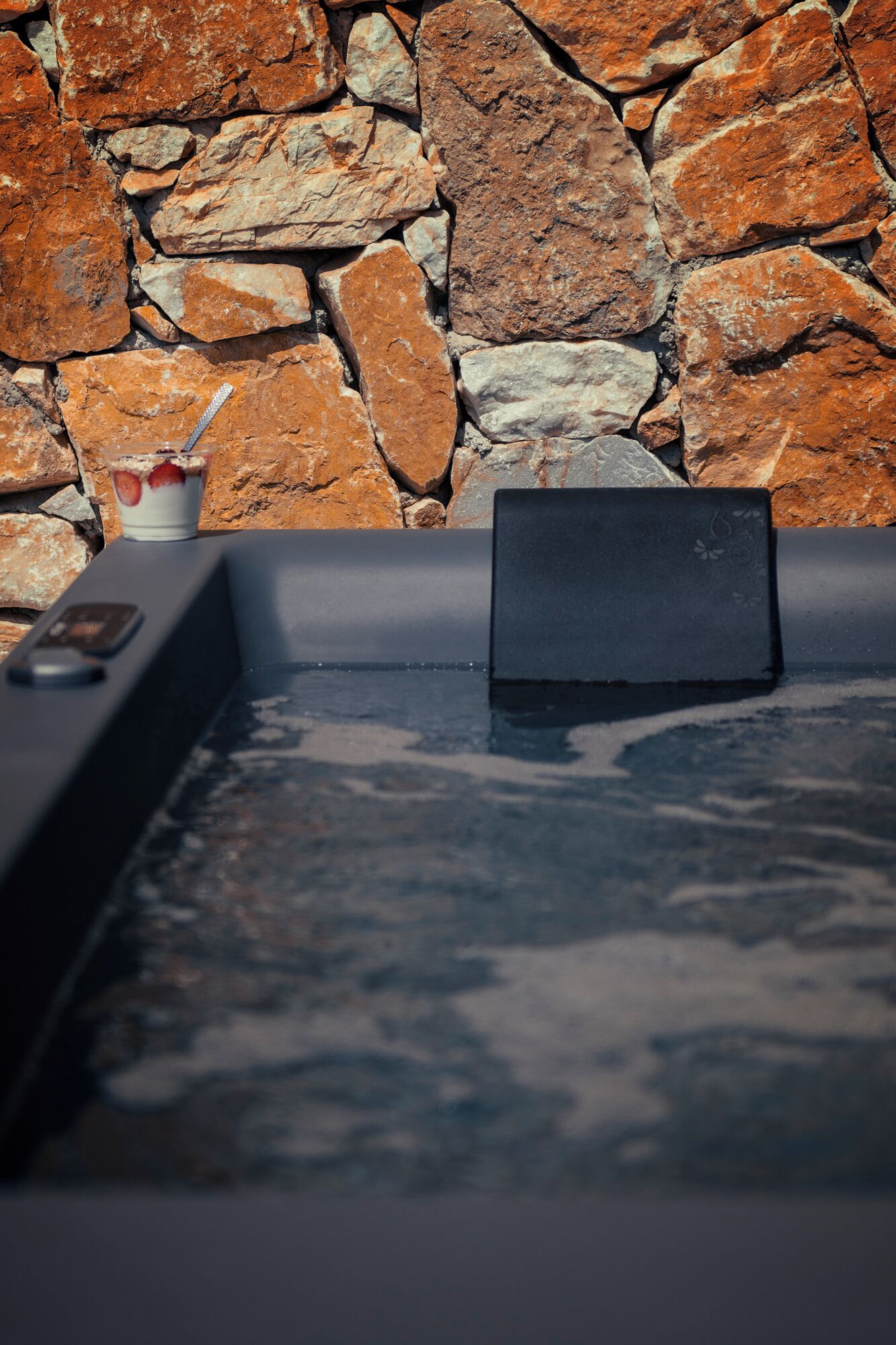 A hot tub with a stone wall in the background.