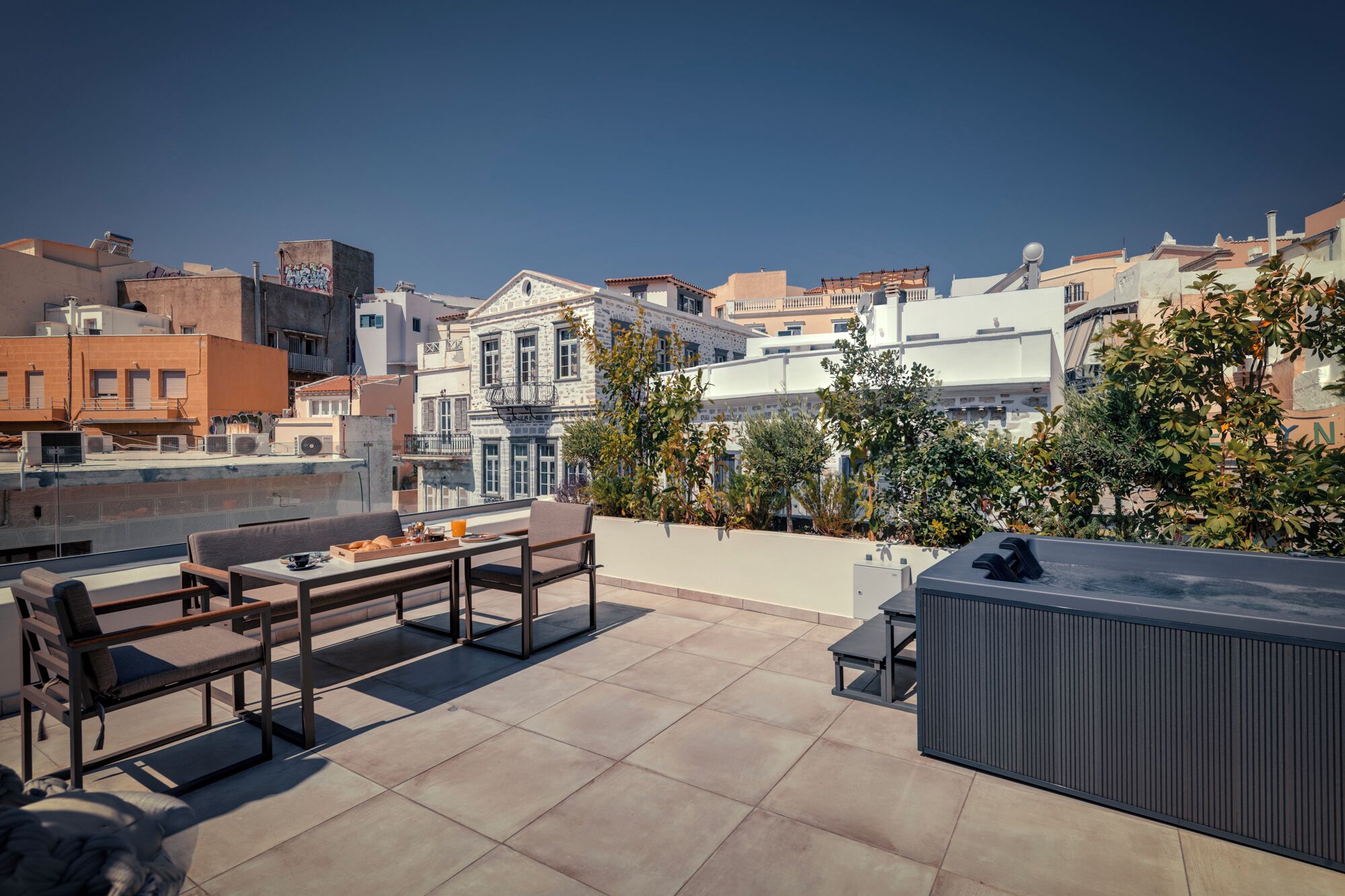 A rooftop terrace with a table, chairs, and a hot tub.