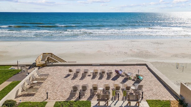 A beachside area with sun loungers and a staircase leading to a higher level.