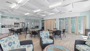 A spacious indoor area with a dining table surrounded by chairs, a sofa, and a ceiling fan.