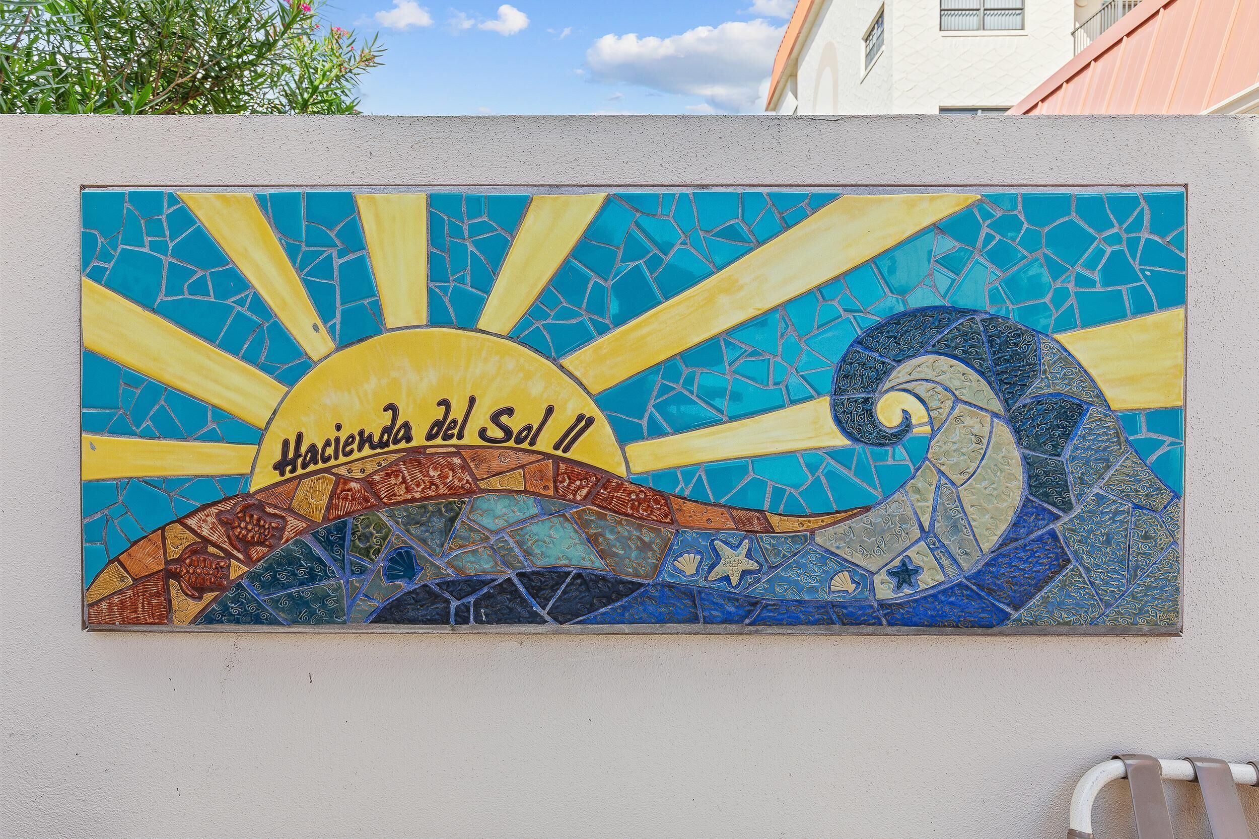 Une enseigne en mosaïque représentant un soleil et des vagues, avec l’inscription « Hacienda del Sol 11 ».