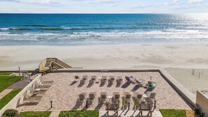 Un espace aménagé au bord de la plage, avec des chaises longues et un escalier menant à un niveau supérieur.