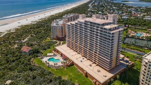 Un hôtel de grande hauteur, avec de nombreux étages, une piscine et une vue sur la plage.