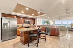 A modern kitchen with a central island, stainless steel appliances, and a view to the outside.