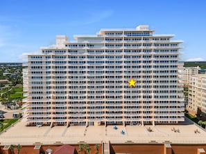 A multi-story hotel with a uniform facade, balconies, and a rooftop terrace with seating.