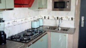 A compact kitchen with a gas stove, a microwave, and a sink. - Upstairs Luxury (Lusaka)