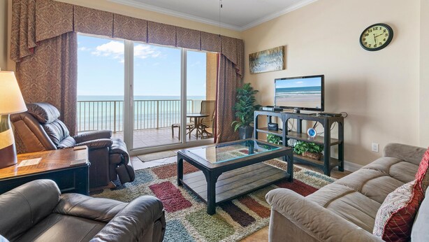 A living room with a sofa, armchair, coffee table, and a television on a stand. - Malibu 803 (New Smyrna Beach)