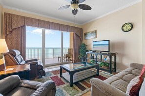A living room with a sofa, armchair, coffee table, and a television on a stand. - Malibu 803 (New Smyrna Beach)