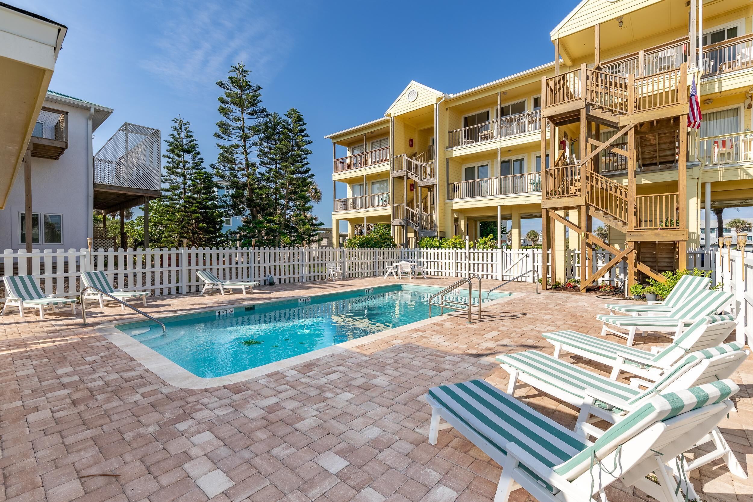 Un espace piscine avec des chaises longues et une terrasse en bois.