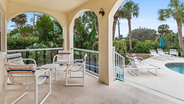 A covered outdoor area with lounge chairs and a pool. - Ocean's Edge (New Smyrna Beach)